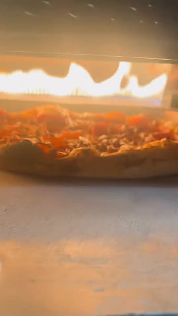 A pizza baking in the flames of Giani’s oven